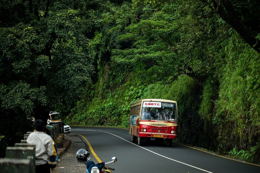 There is a bus in this picture. There is greenery in the background.